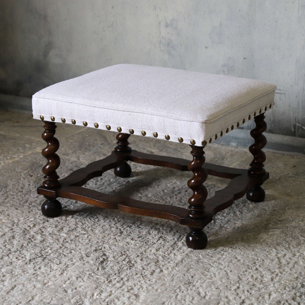 A square upholstered stool with neutral fabric and brass nailhead trim, supported by dark turned barley-twist legs and a serpentine stretcher on ball feet. View III