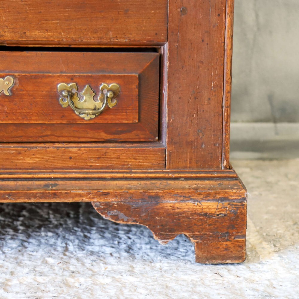 An 18th-century pine mule chest with two raised front panels, two lower drawers, and original brass hardware on a bracket base. View VII