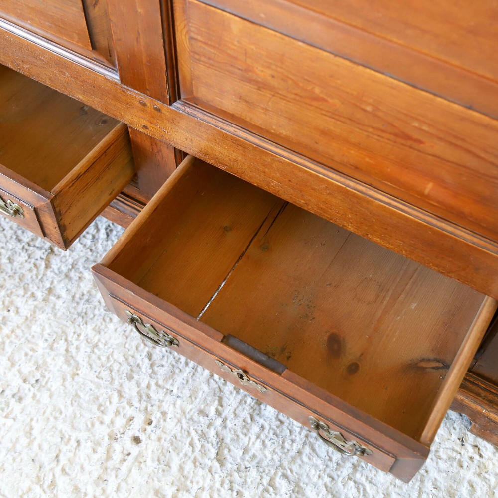 An 18th-century pine mule chest with two raised front panels, two lower drawers, and original brass hardware on a bracket base. View XIII