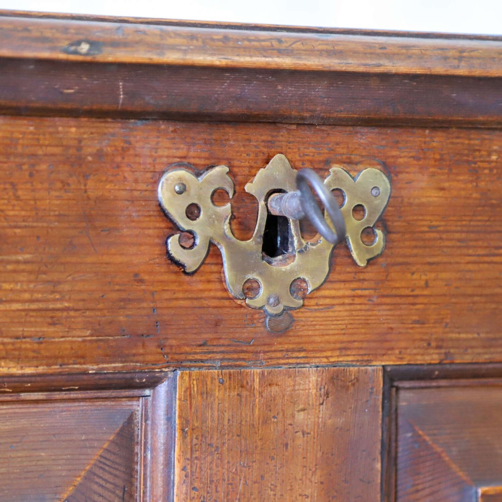 An 18th-century pine mule chest with two raised front panels, two lower drawers, and original brass hardware on a bracket base. View XV