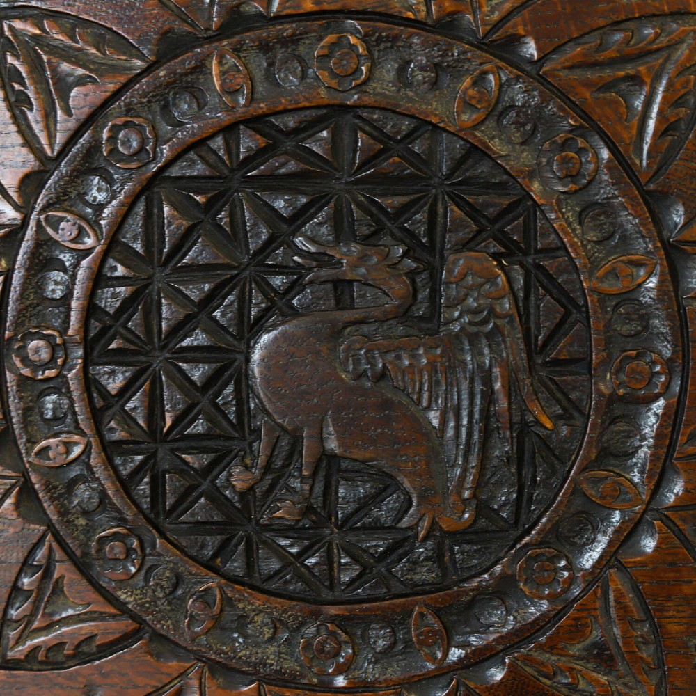 An octagonal dark carved oak panel featuring a central winged mythical creature within geometric latticework and leaf motifs. View III