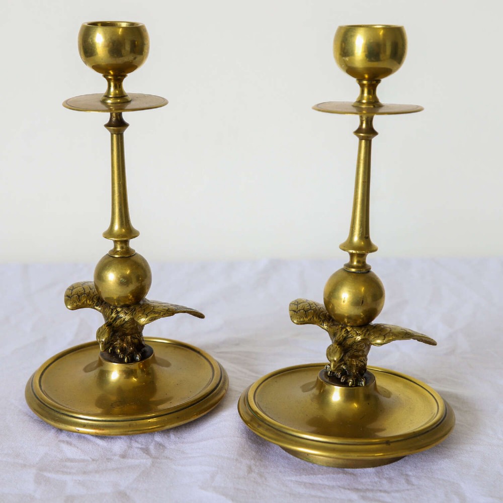 A pair of Georgian brass candlesticks featuring spread-winged eagle motifs supporting tapering stems above circular dished bases. View IV