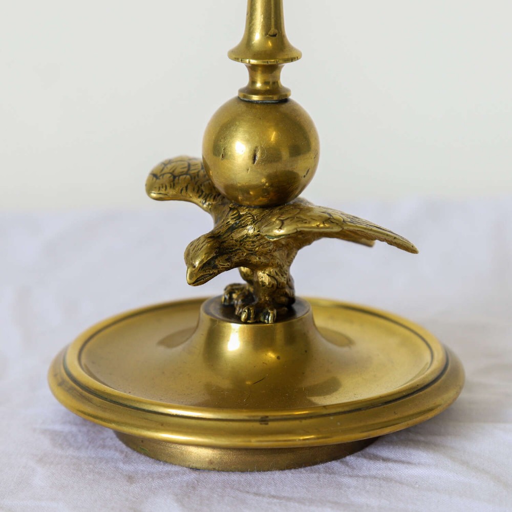 A pair of Georgian brass candlesticks featuring spread-winged eagle motifs supporting tapering stems above circular dished bases. View V