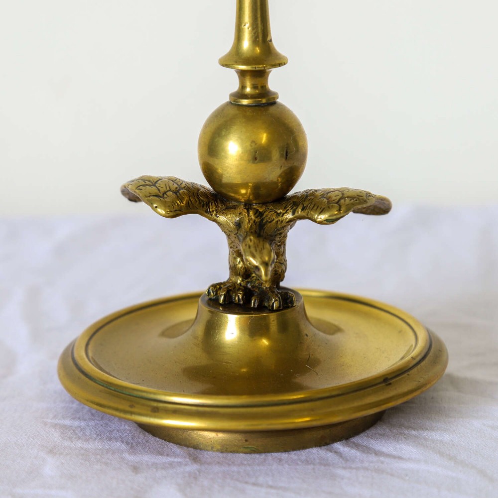 A pair of Georgian brass candlesticks featuring spread-winged eagle motifs supporting tapering stems above circular dished bases. View VI