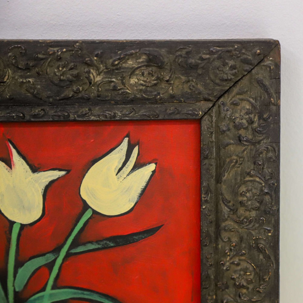 A 1930s Swedish still life oil painting depicting white tulips in a patterned ceramic vase next to a blue jug on a red background, set inside a carved dark wooden frame. View IV