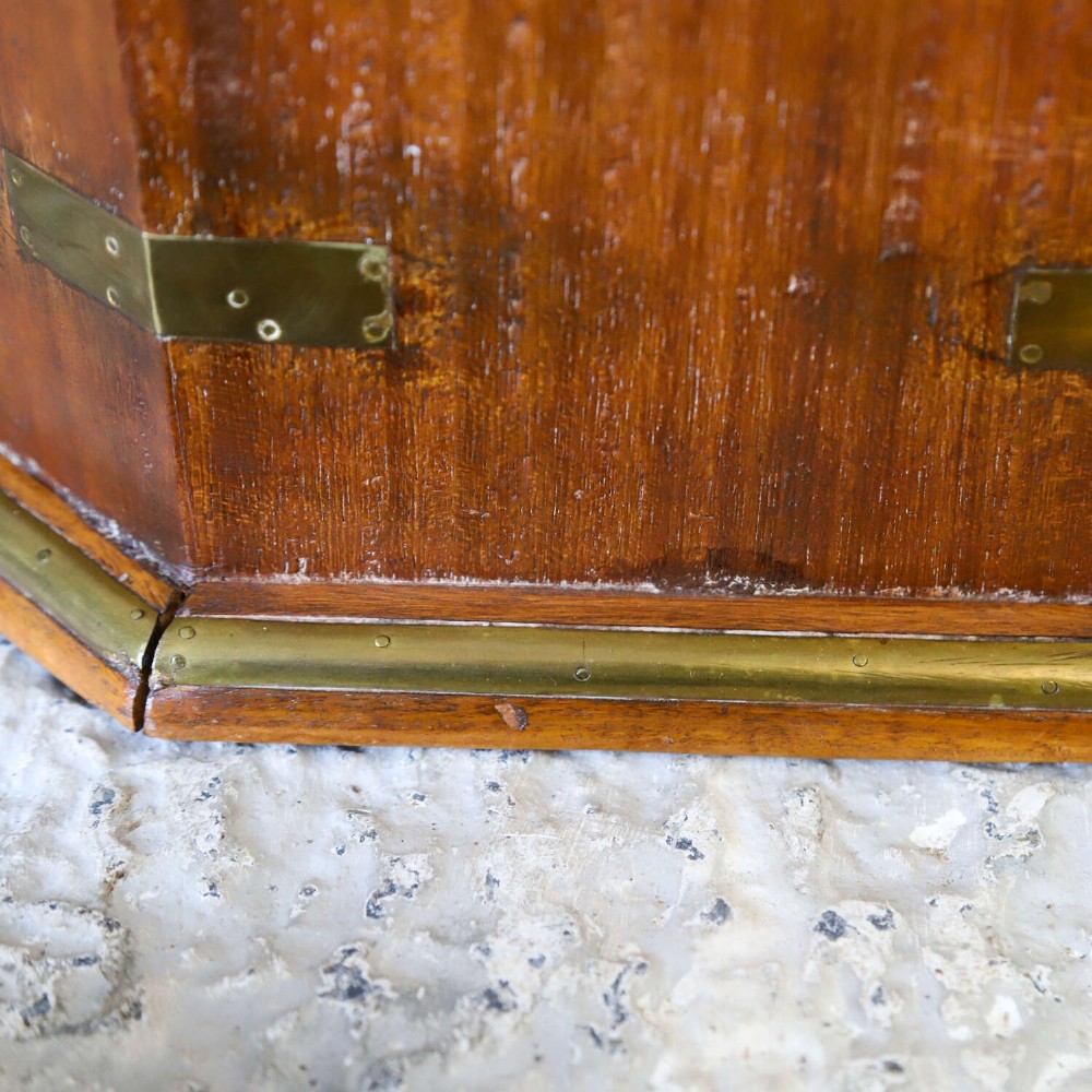 An octagonal antique wooden campaign chest featuring a hinged lift-up top, brass corner brackets, strapwork, and side carrying handles against a white background. View X