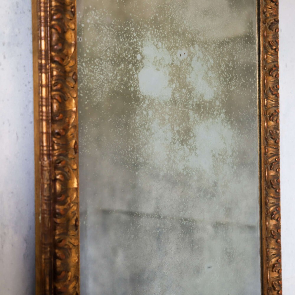 A tall rectangular nineteenth-century French mirror featuring a gilded wood frame with relief pattern molding and heavily foxed mirrored glass. View III