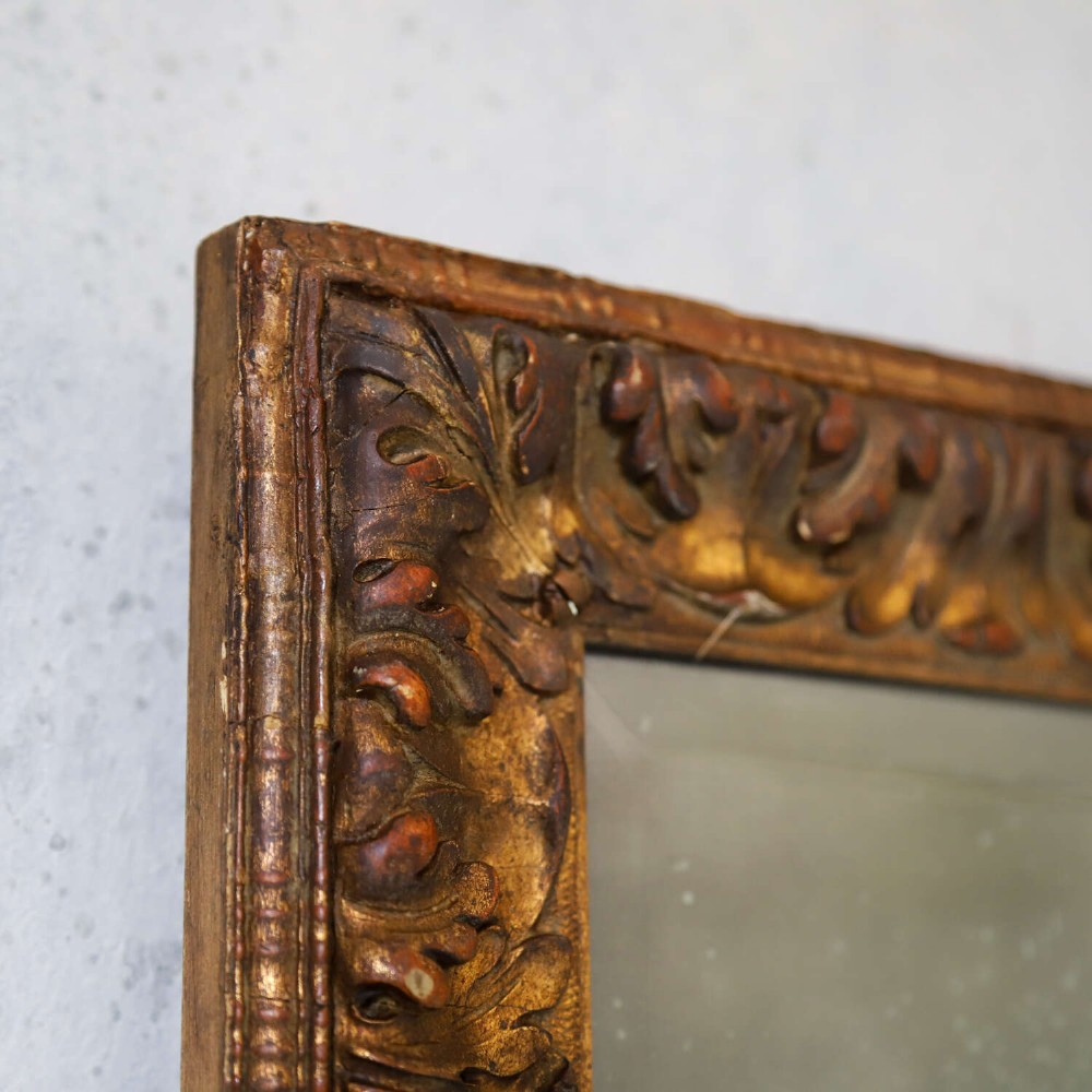 A tall rectangular nineteenth-century French mirror featuring a gilded wood frame with relief pattern molding and heavily foxed mirrored glass. View IV
