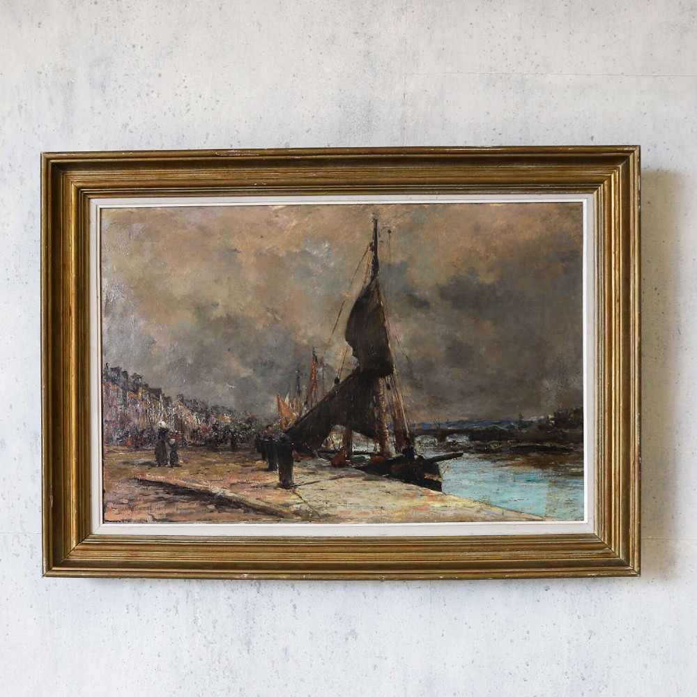 A 19th-century framed oil painting on canvas depicting sailboats moored along a harbour quay under a cloudy sky. View II