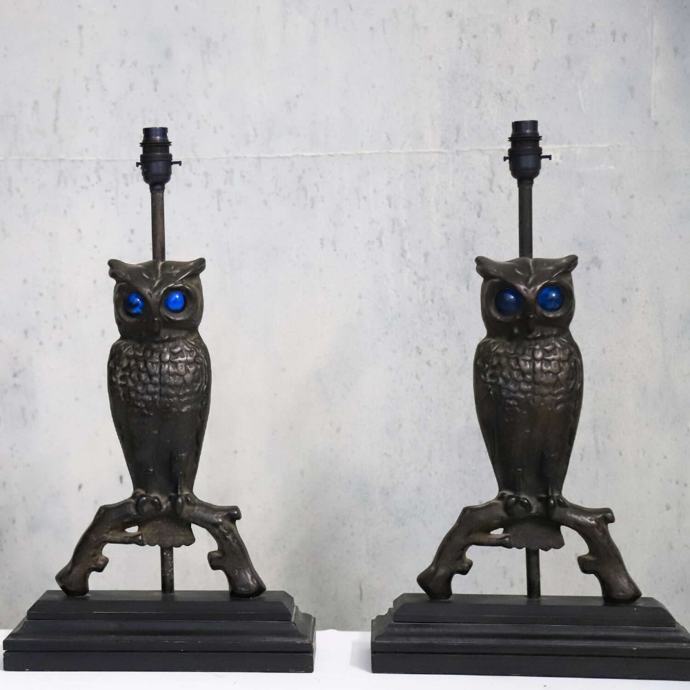A pair of dark cast iron owl table lamps with bright blue glass eyes, perched on branch bases mounted on black plinths. View IV