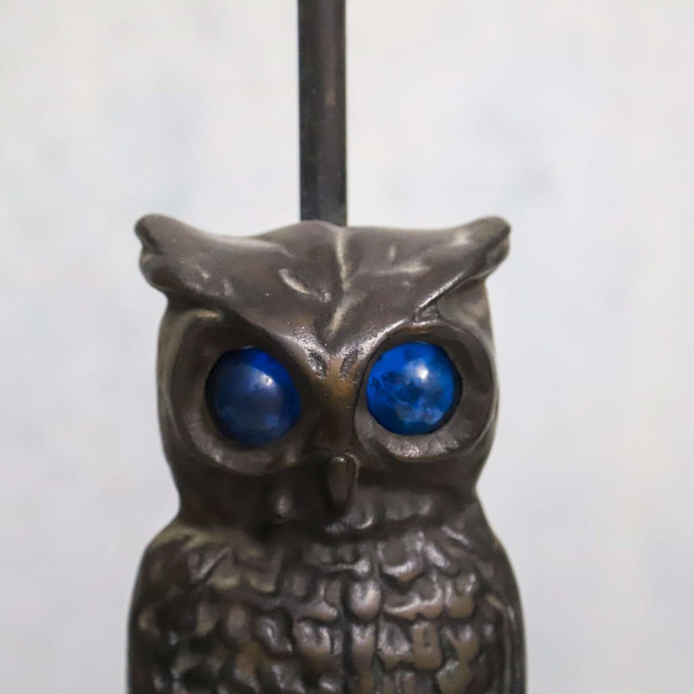 A pair of dark cast iron owl table lamps with bright blue glass eyes, perched on branch bases mounted on black plinths. View V