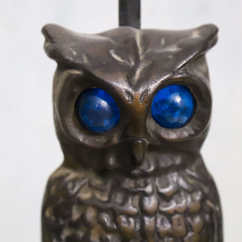 A pair of dark cast iron owl table lamps with bright blue glass eyes, perched on branch bases mounted on black plinths. View VII