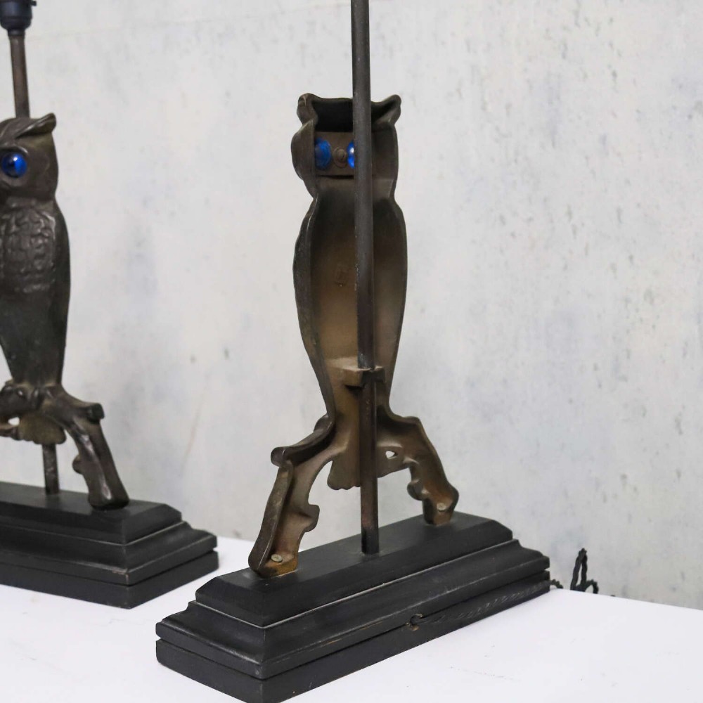 A pair of dark cast iron owl table lamps with bright blue glass eyes, perched on branch bases mounted on black plinths. View IX