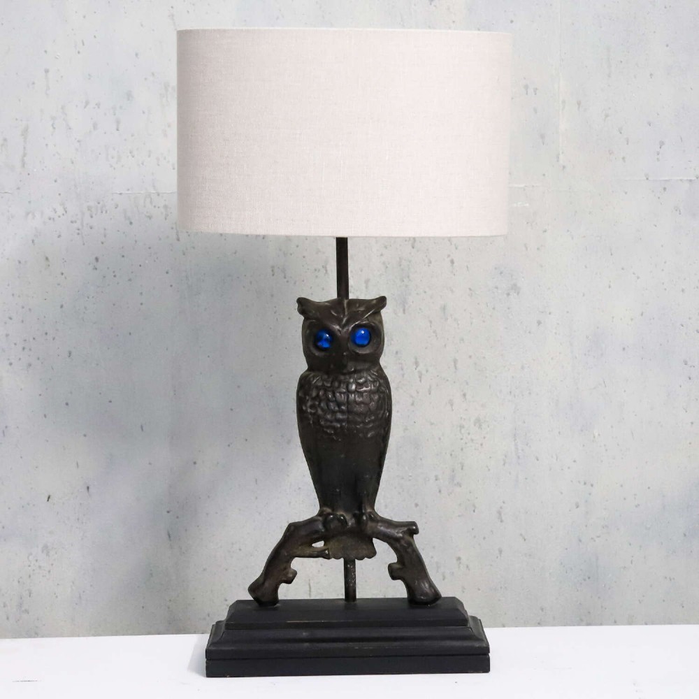 A pair of dark cast iron owl table lamps with bright blue glass eyes, perched on branch bases mounted on black plinths. View XI