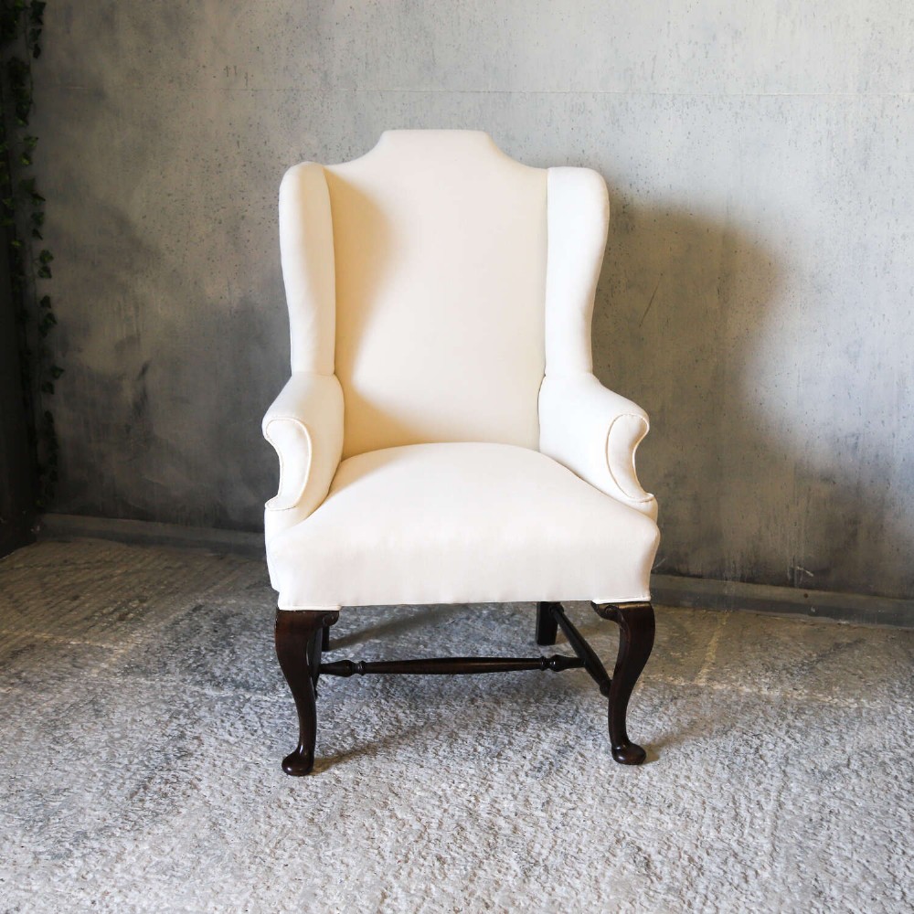 A 19th-century wingback armchair newly upholstered in plain cream calico fabric with dark carved timber cabriole front legs. View II