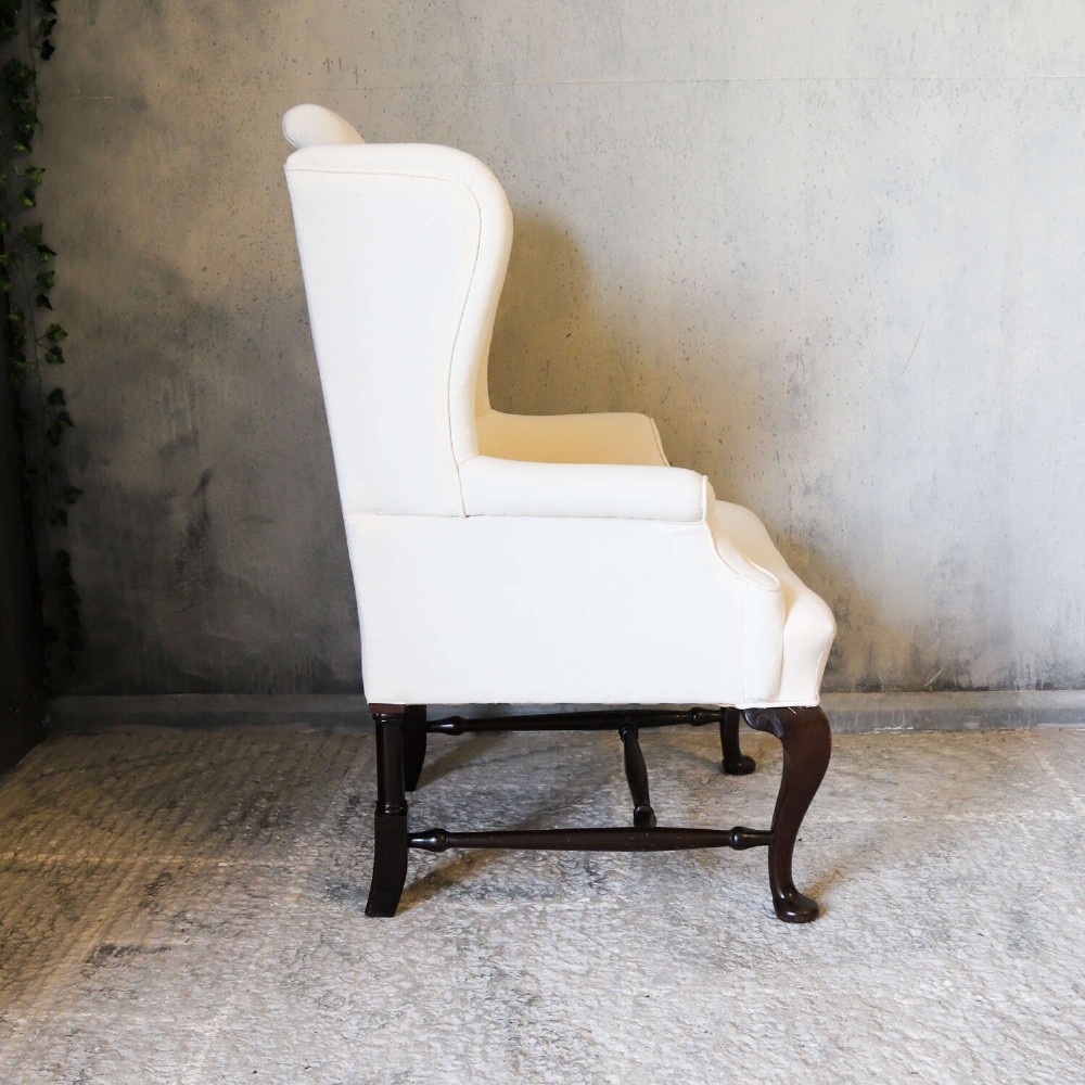 A 19th-century wingback armchair newly upholstered in plain cream calico fabric with dark carved timber cabriole front legs. View IV