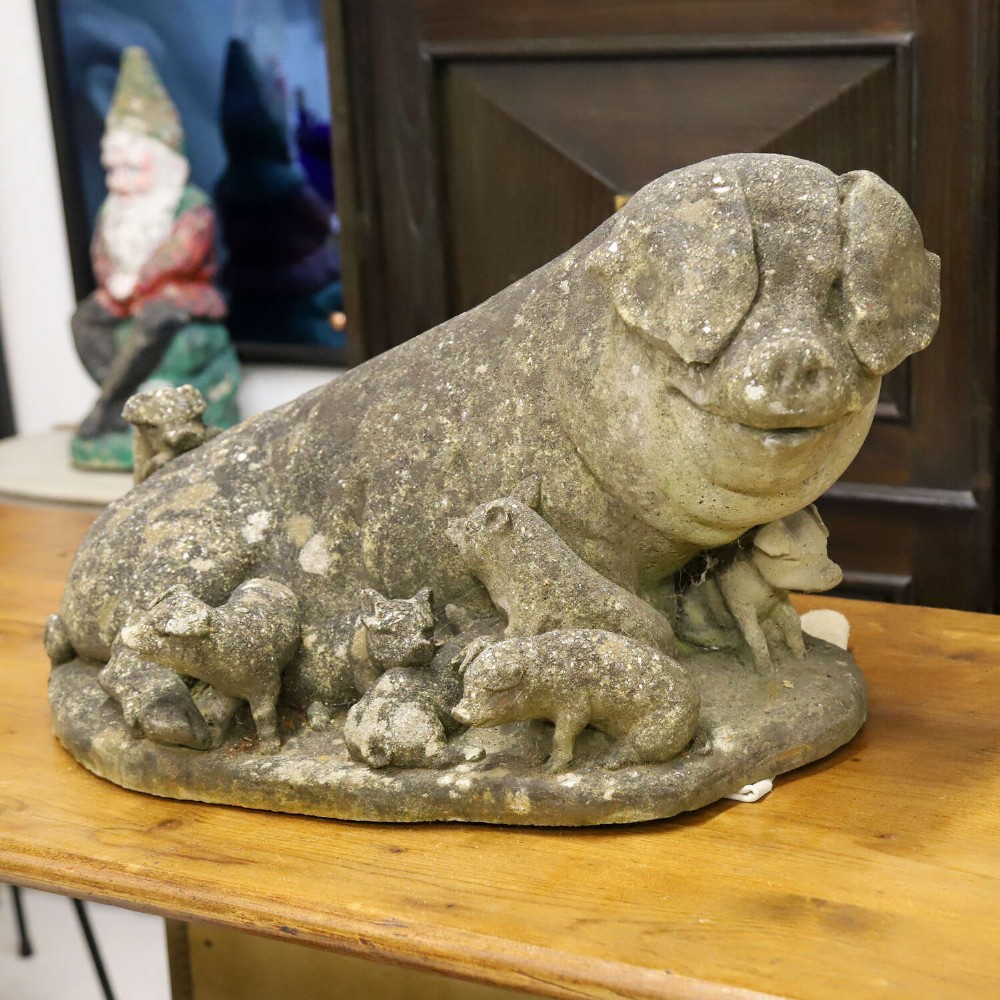 A weathered cast stone garden statue featuring a reclining sow flanked by seven small piglets on a moulded oval base. View III