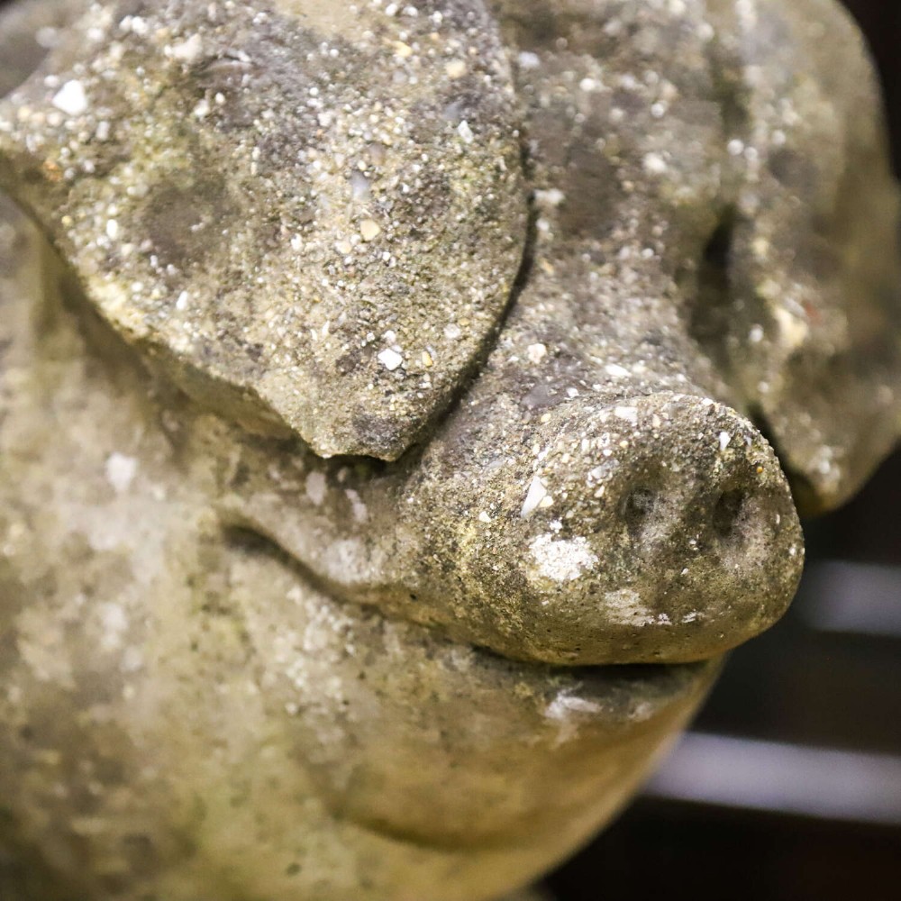 A weathered cast stone garden statue featuring a reclining sow flanked by seven small piglets on a moulded oval base. View XIII