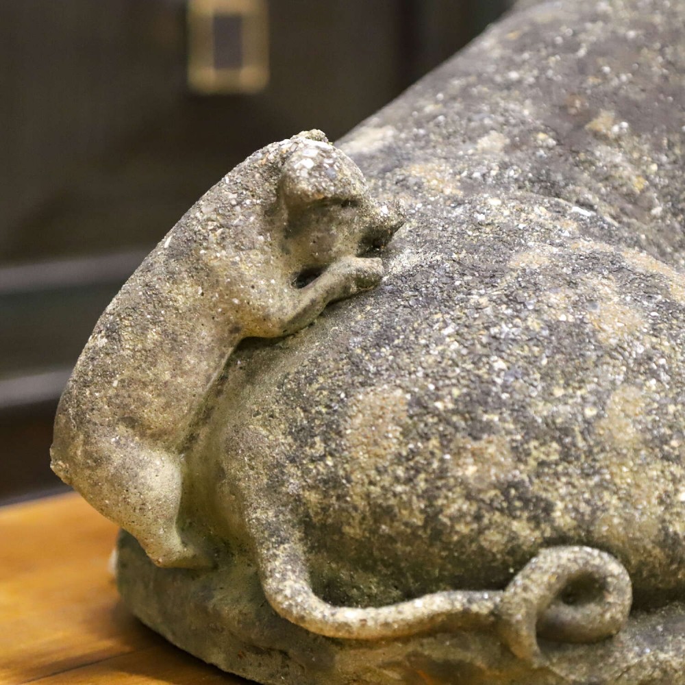 A weathered cast stone garden statue featuring a reclining sow flanked by seven small piglets on a moulded oval base. View XV