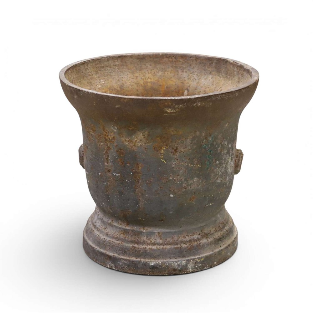 A nineteenth-century cast iron mortar featuring a flared upper rim, two side lug handles, and a moulded circular base with a patinated metal surface.