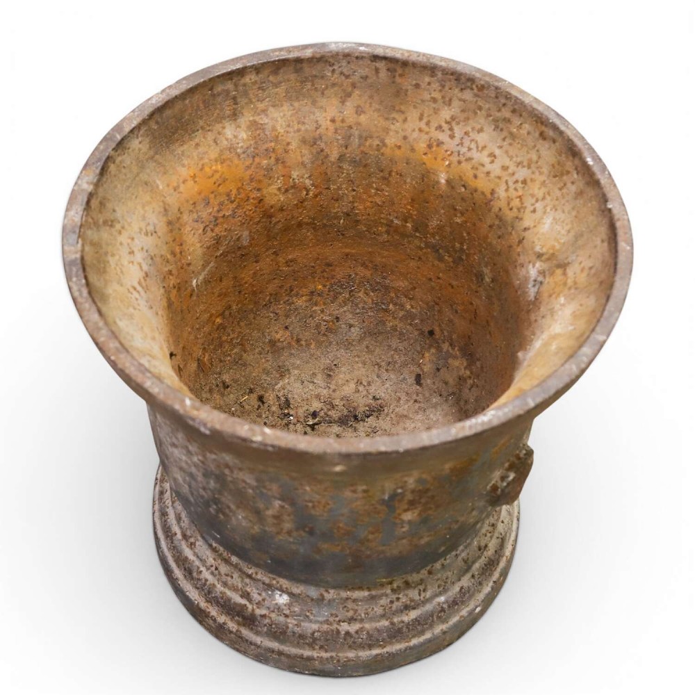 A nineteenth-century cast iron mortar featuring a flared upper rim, two side lug handles, and a moulded circular base with a patinated metal surface. View V