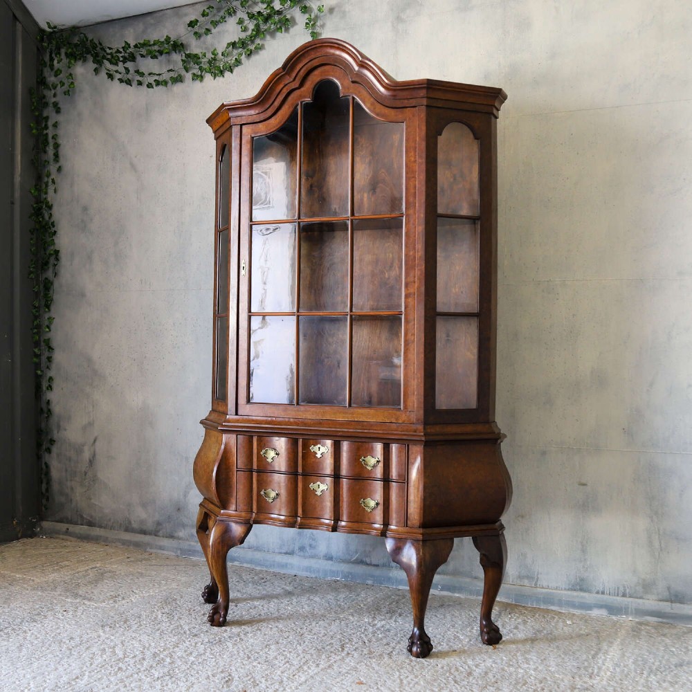 A Dutch walnut-veneered glazed cabinet featuring an arched top, glass paned upper doors, a shaped lower drawer section, and cabriole legs with claw and ball feet. View III