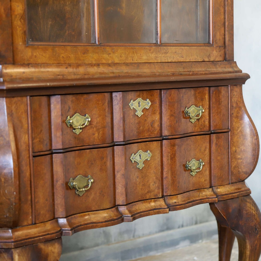 A Dutch walnut-veneered glazed cabinet featuring an arched top, glass paned upper doors, a shaped lower drawer section, and cabriole legs with claw and ball feet. View IV