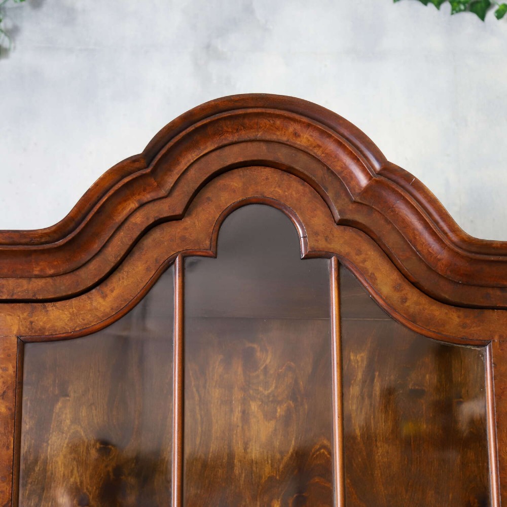 A Dutch walnut-veneered glazed cabinet featuring an arched top, glass paned upper doors, a shaped lower drawer section, and cabriole legs with claw and ball feet. View VIII