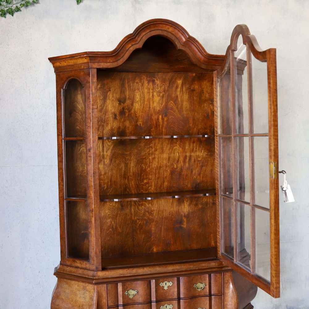 A Dutch walnut-veneered glazed cabinet featuring an arched top, glass paned upper doors, a shaped lower drawer section, and cabriole legs with claw and ball feet. View IX