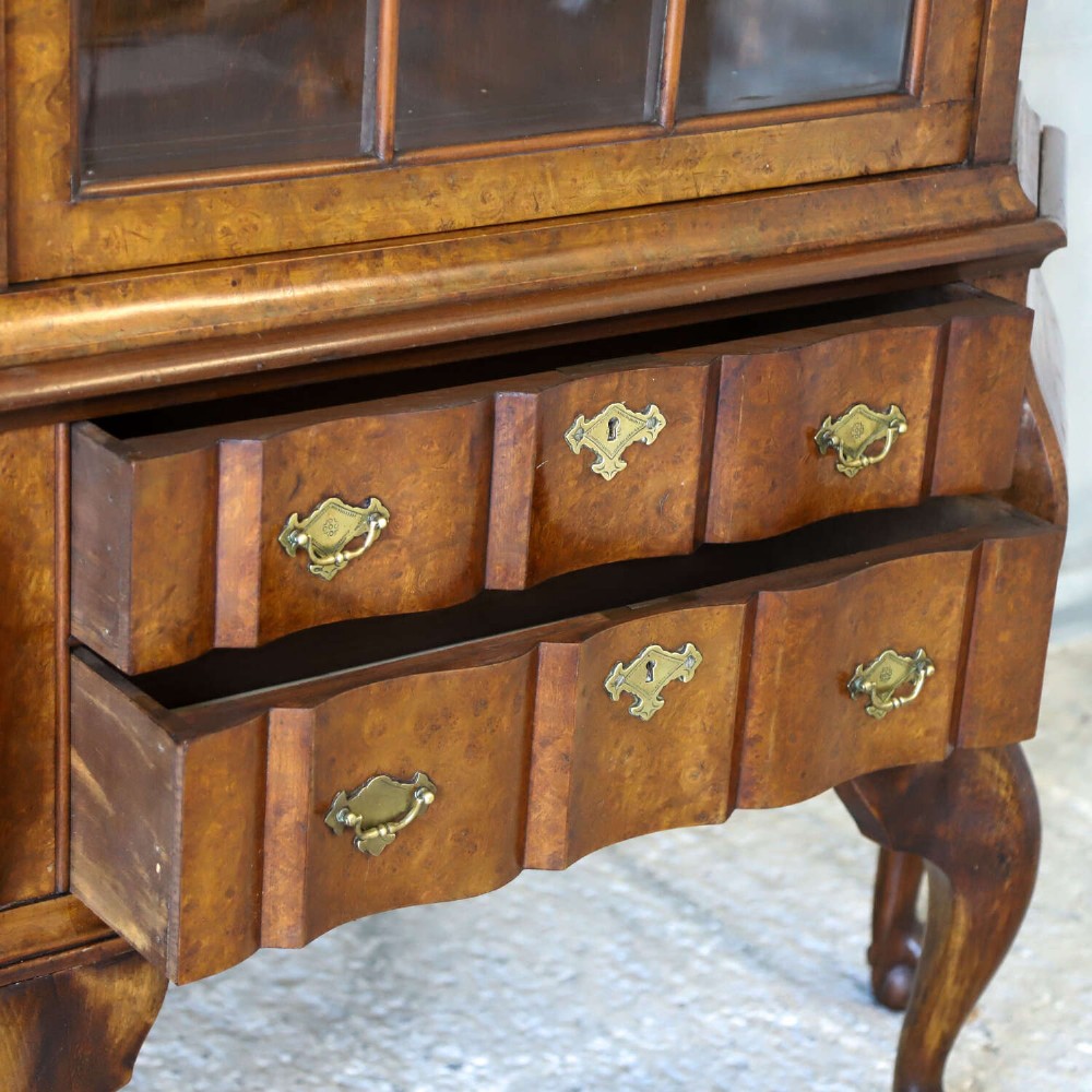 A Dutch walnut-veneered glazed cabinet featuring an arched top, glass paned upper doors, a shaped lower drawer section, and cabriole legs with claw and ball feet. View X
