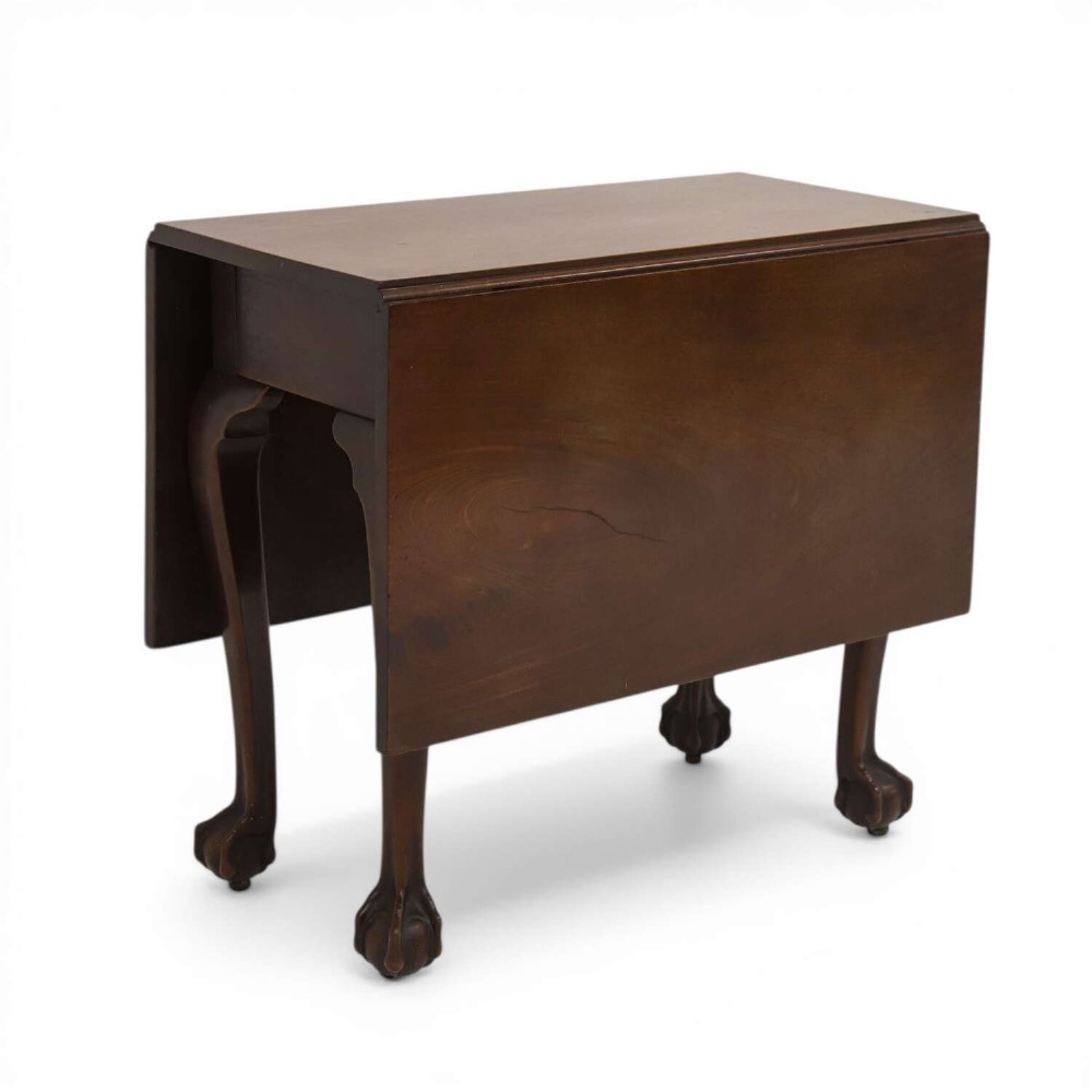 A George II mahogany drop-leaf dining table shown with leaves folded down, supported on four cabriole legs with carved claw-and-ball feet.
