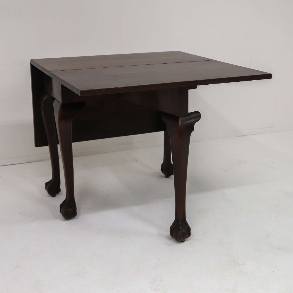 A George II mahogany drop-leaf dining table shown with leaves folded down, supported on four cabriole legs with carved claw-and-ball feet. View IV