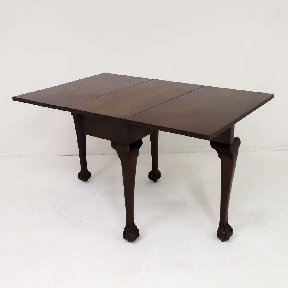 A George II mahogany drop-leaf dining table shown with leaves folded down, supported on four cabriole legs with carved claw-and-ball feet. View V