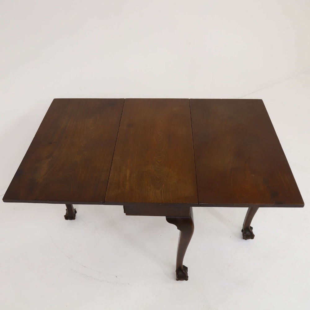 A George II mahogany drop-leaf dining table shown with leaves folded down, supported on four cabriole legs with carved claw-and-ball feet. View VII