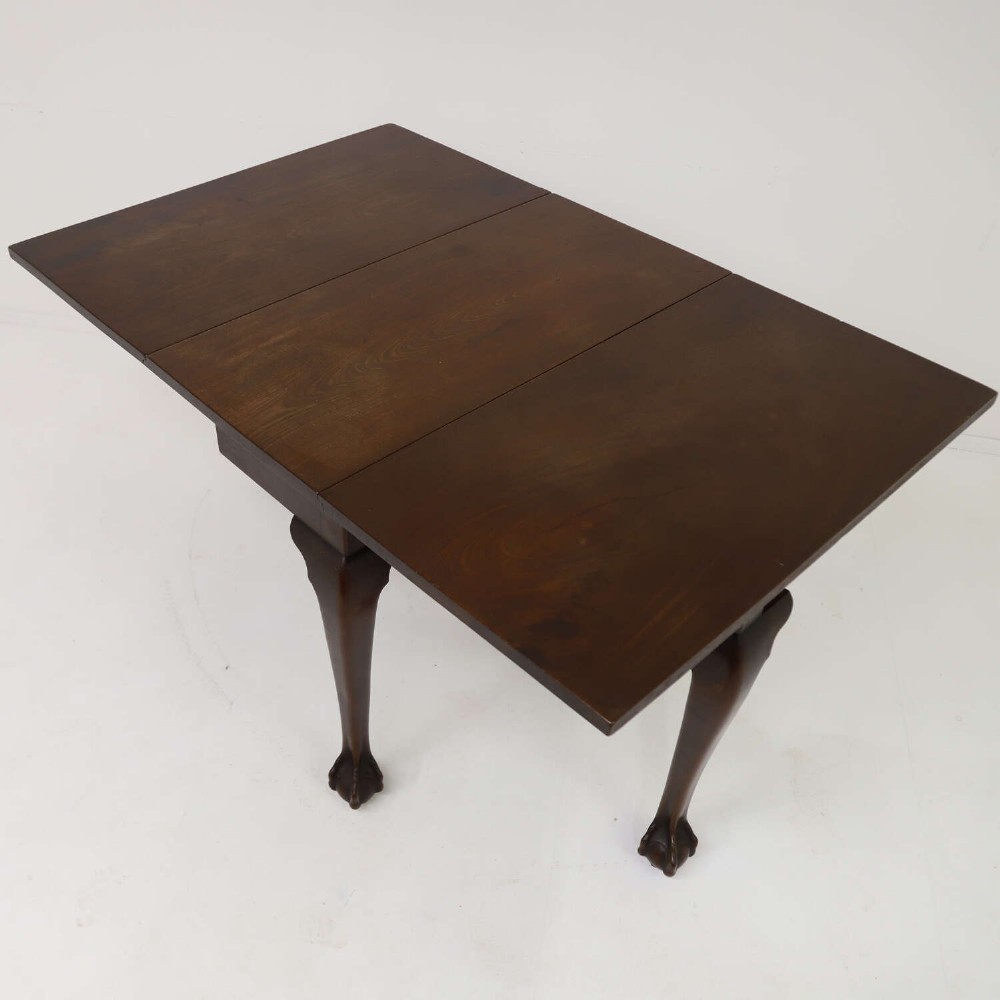A George II mahogany drop-leaf dining table shown with leaves folded down, supported on four cabriole legs with carved claw-and-ball feet. View X