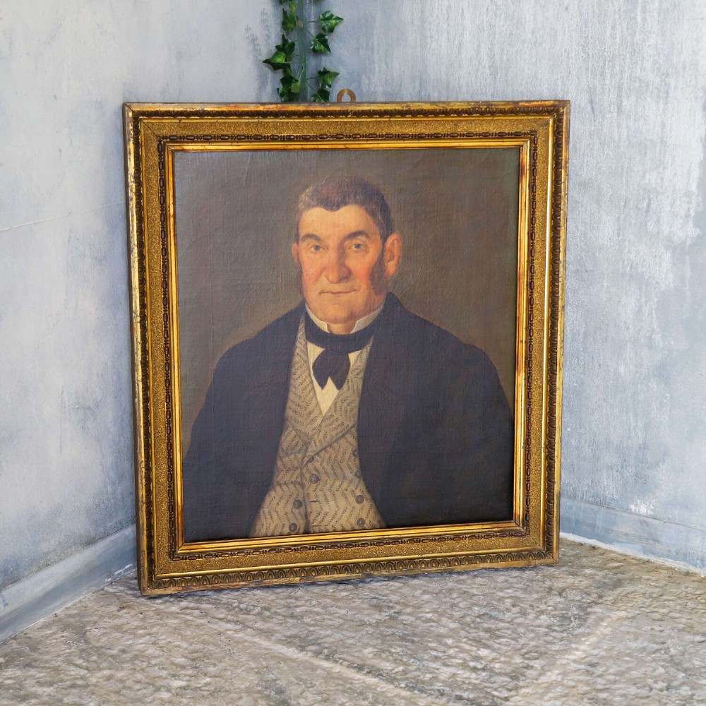 An antique oil painting depicting a male subject wearing a patterned waistcoat and black jacket, set in a gilded frame. View XI