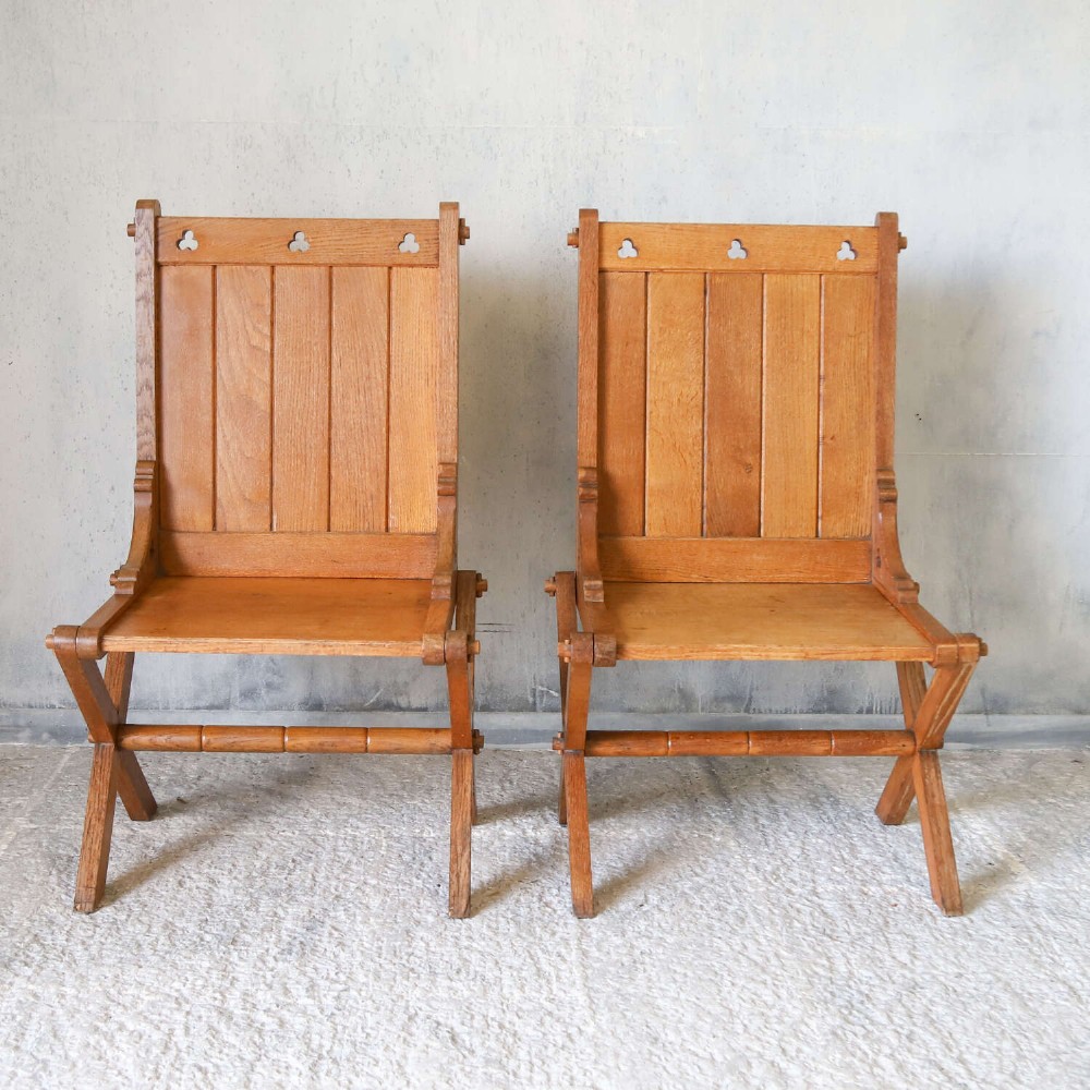 A pair of warm brown oak Glastonbury chairs featuring panelled backs with trefoil cut-outs and exposed pegged X-frame legs. View IV
