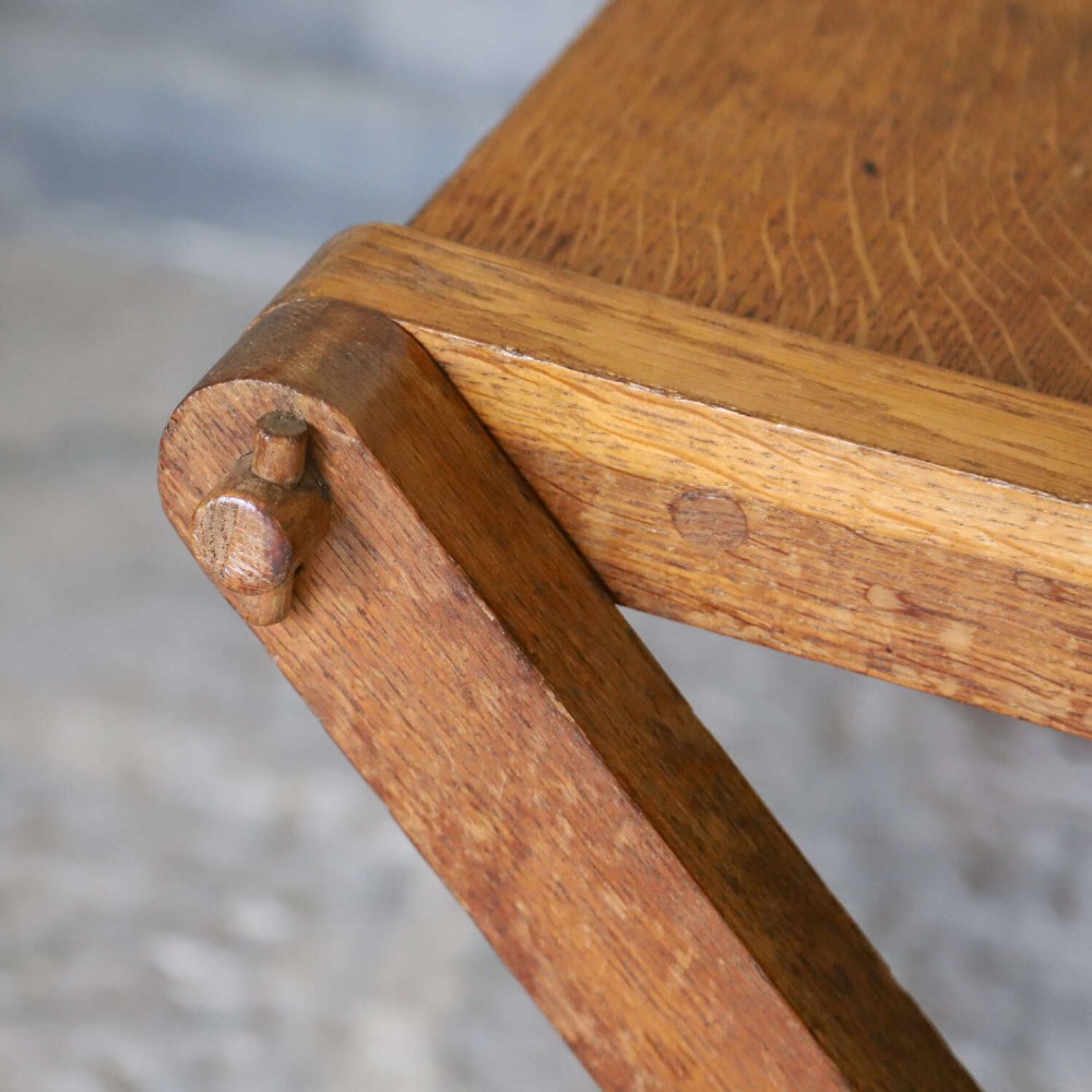 A pair of warm brown oak Glastonbury chairs featuring panelled backs with trefoil cut-outs and exposed pegged X-frame legs. View XII