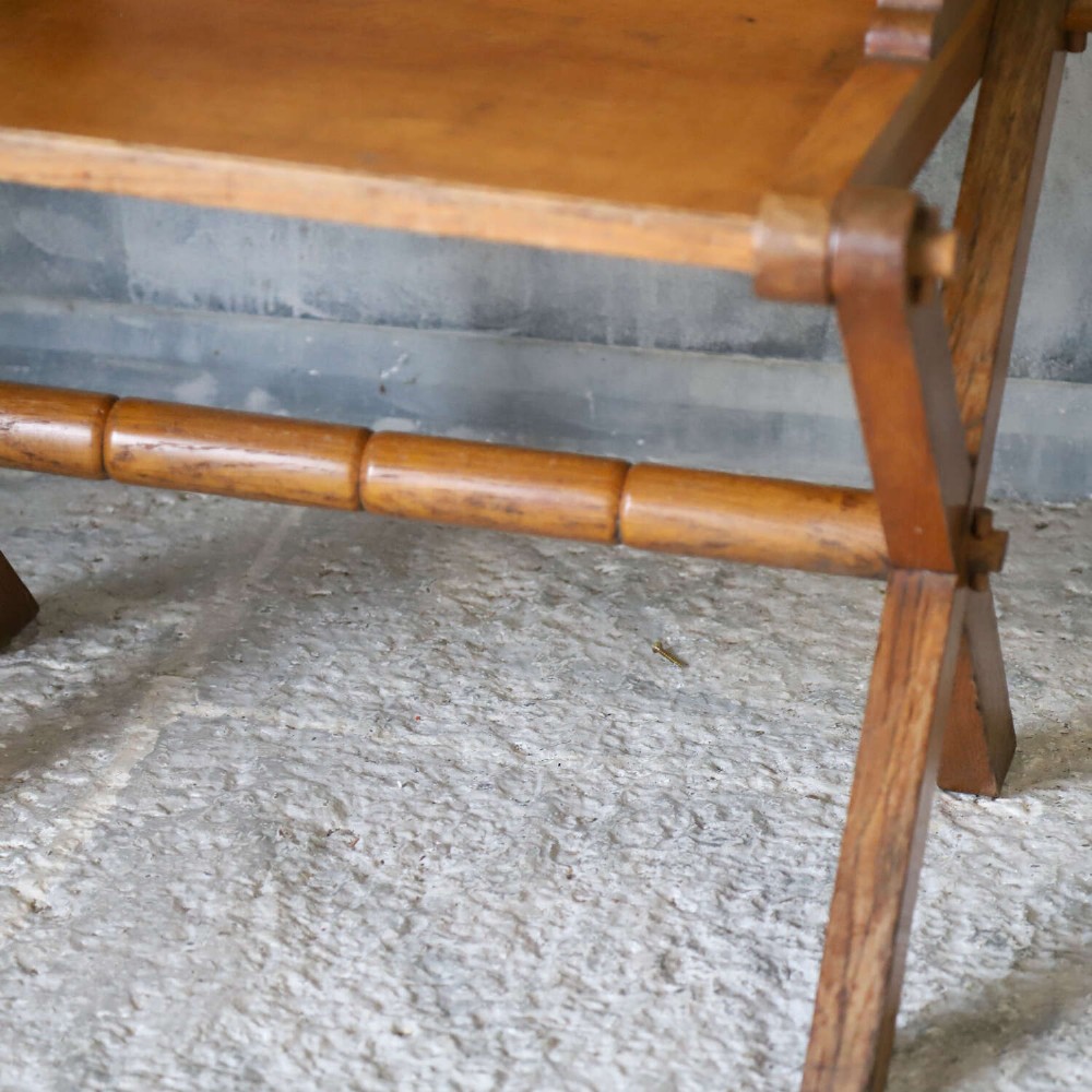 A pair of warm brown oak Glastonbury chairs featuring panelled backs with trefoil cut-outs and exposed pegged X-frame legs. View XV