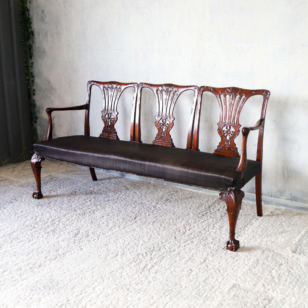 An Edwardian mahogany three-seater settee featuring three carved Chippendale-style pierced back splats, curved armrests, cabriole front legs with ball and claw feet, and a dark upholstered seat. View III