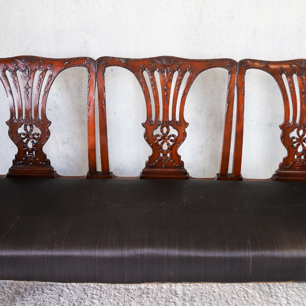 An Edwardian mahogany three-seater settee featuring three carved Chippendale-style pierced back splats, curved armrests, cabriole front legs with ball and claw feet, and a dark upholstered seat. View XI