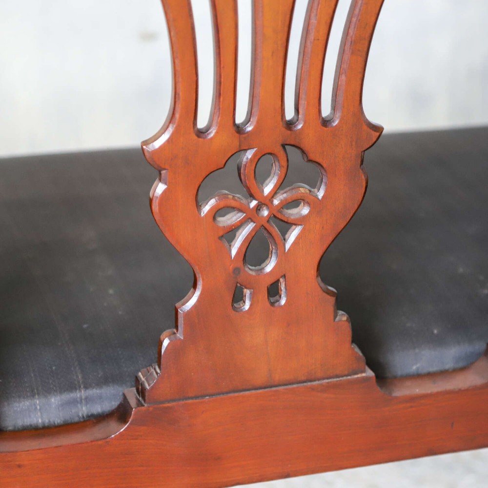 An Edwardian mahogany three-seater settee featuring three carved Chippendale-style pierced back splats, curved armrests, cabriole front legs with ball and claw feet, and a dark upholstered seat. View XV