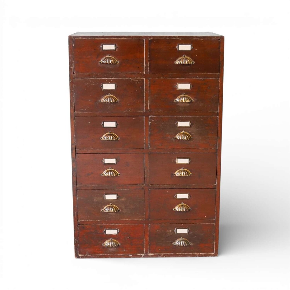 An antique Edwardian dark mahogany bank of twelve drawers featuring brass shell cup handles and label holders.