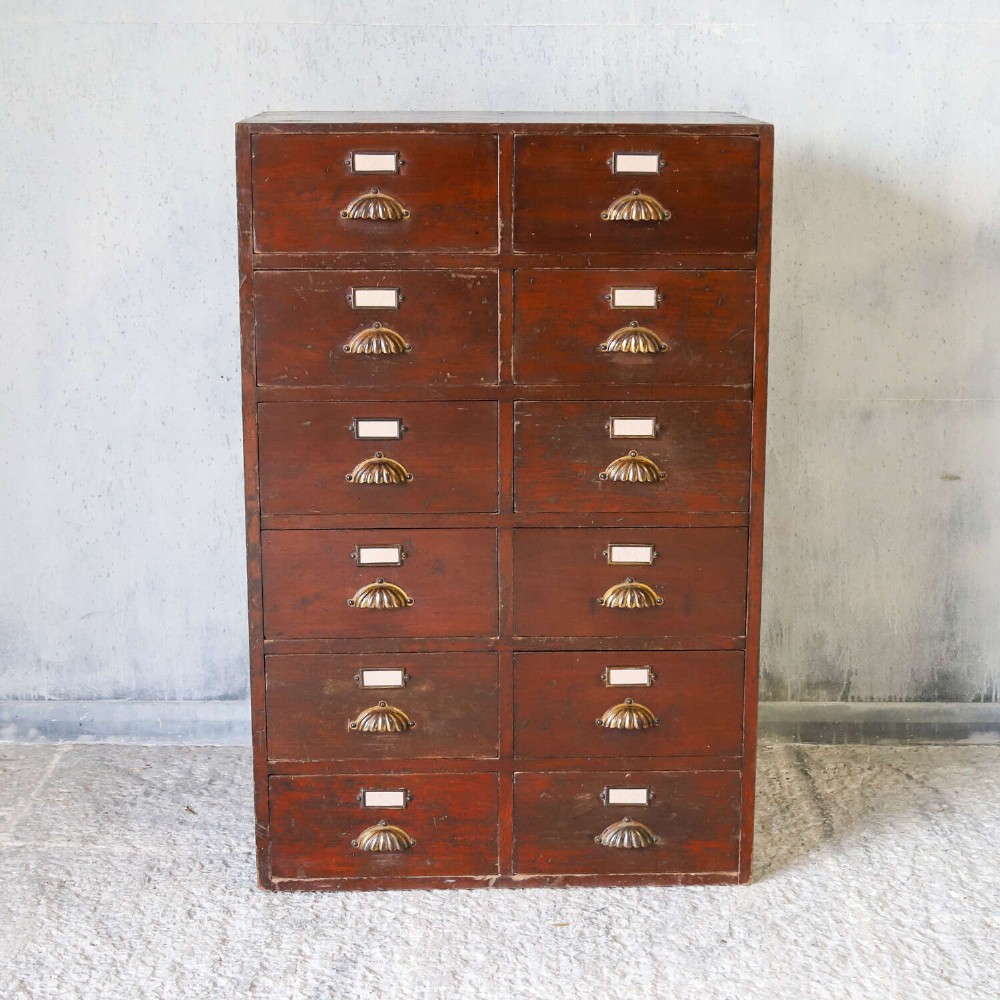 An antique Edwardian dark mahogany bank of twelve drawers featuring brass shell cup handles and label holders. View II