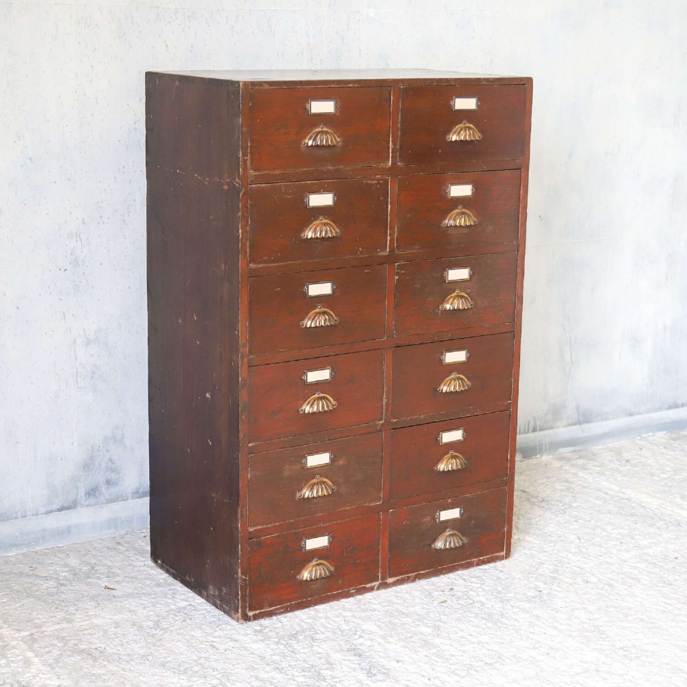 An antique Edwardian dark mahogany bank of twelve drawers featuring brass shell cup handles and label holders. View III