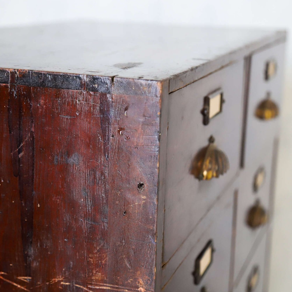 An antique Edwardian dark mahogany bank of twelve drawers featuring brass shell cup handles and label holders. View X