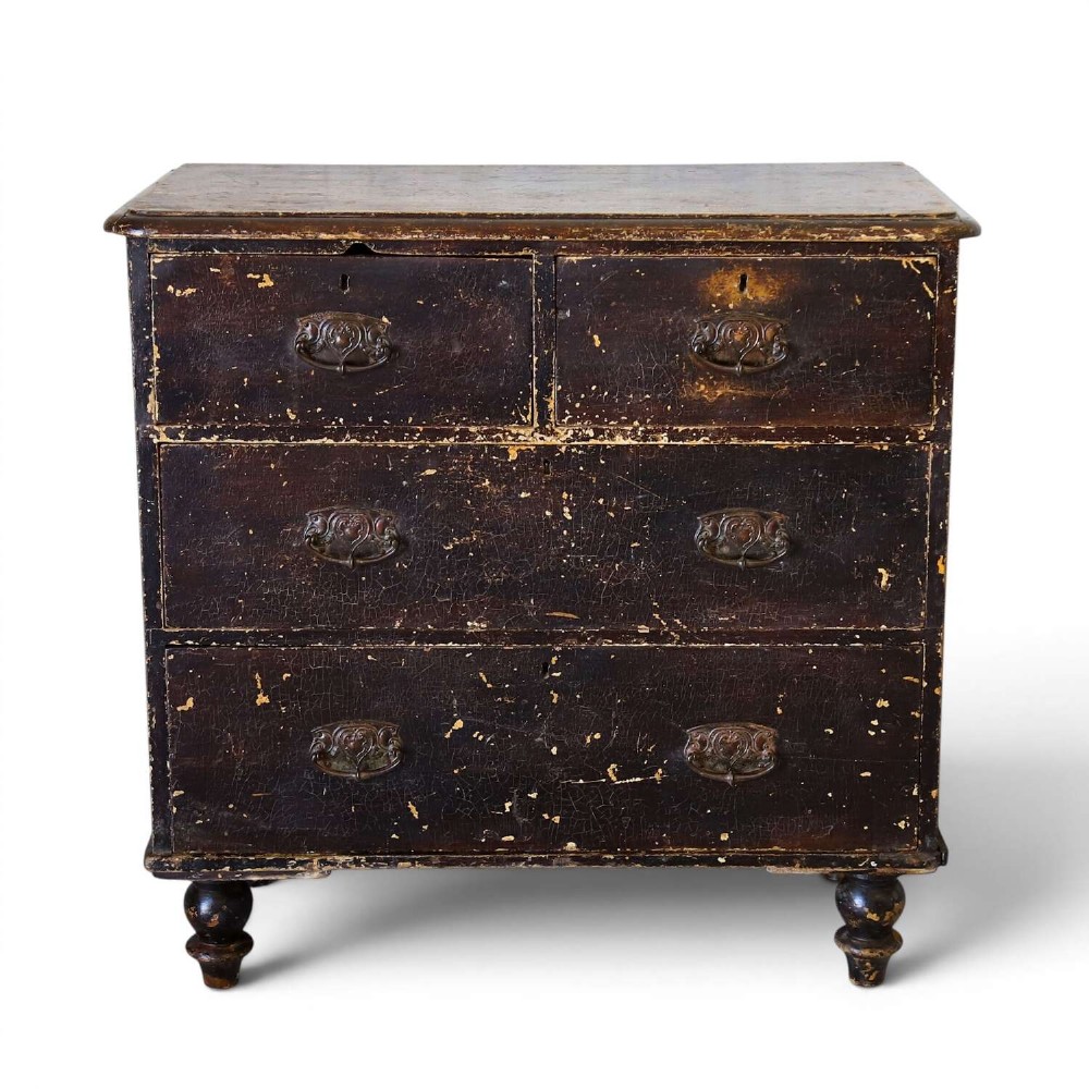 An antique pine chest of drawers featuring a dark brown scumble paint finish, Art Nouveau brass drop handles, two short drawers over two long drawers, and turned feet.