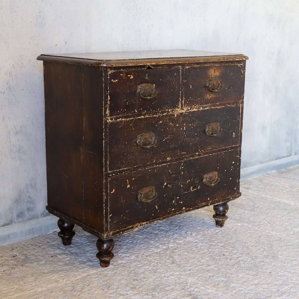 An antique pine chest of drawers featuring a dark brown scumble paint finish, Art Nouveau brass drop handles, two short drawers over two long drawers, and turned feet. View II