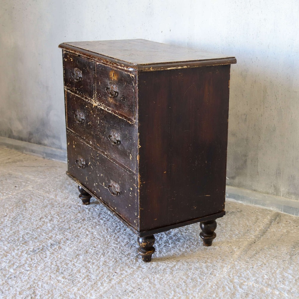 An antique pine chest of drawers featuring a dark brown scumble paint finish, Art Nouveau brass drop handles, two short drawers over two long drawers, and turned feet. View III