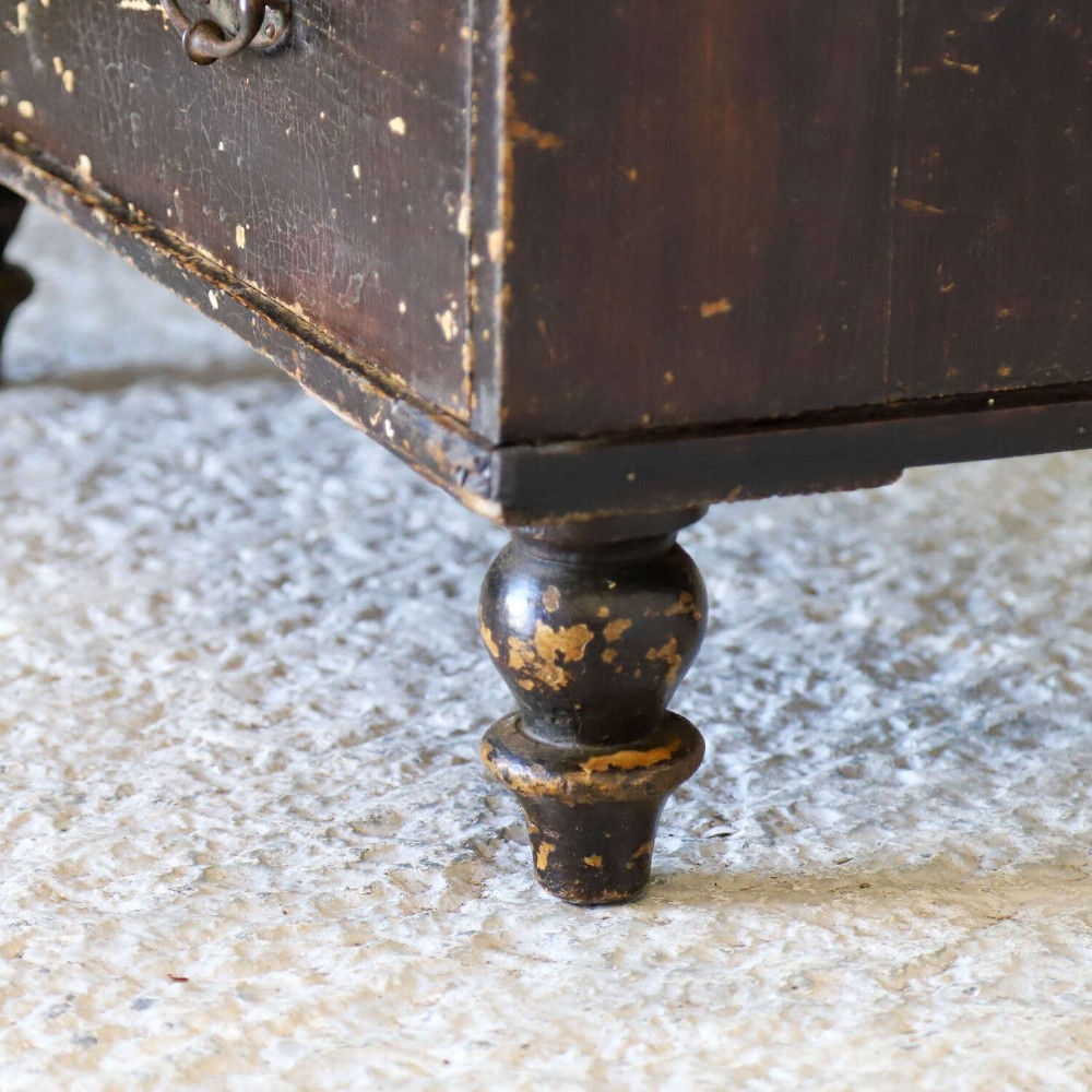 An antique pine chest of drawers featuring a dark brown scumble paint finish, Art Nouveau brass drop handles, two short drawers over two long drawers, and turned feet. View IV
